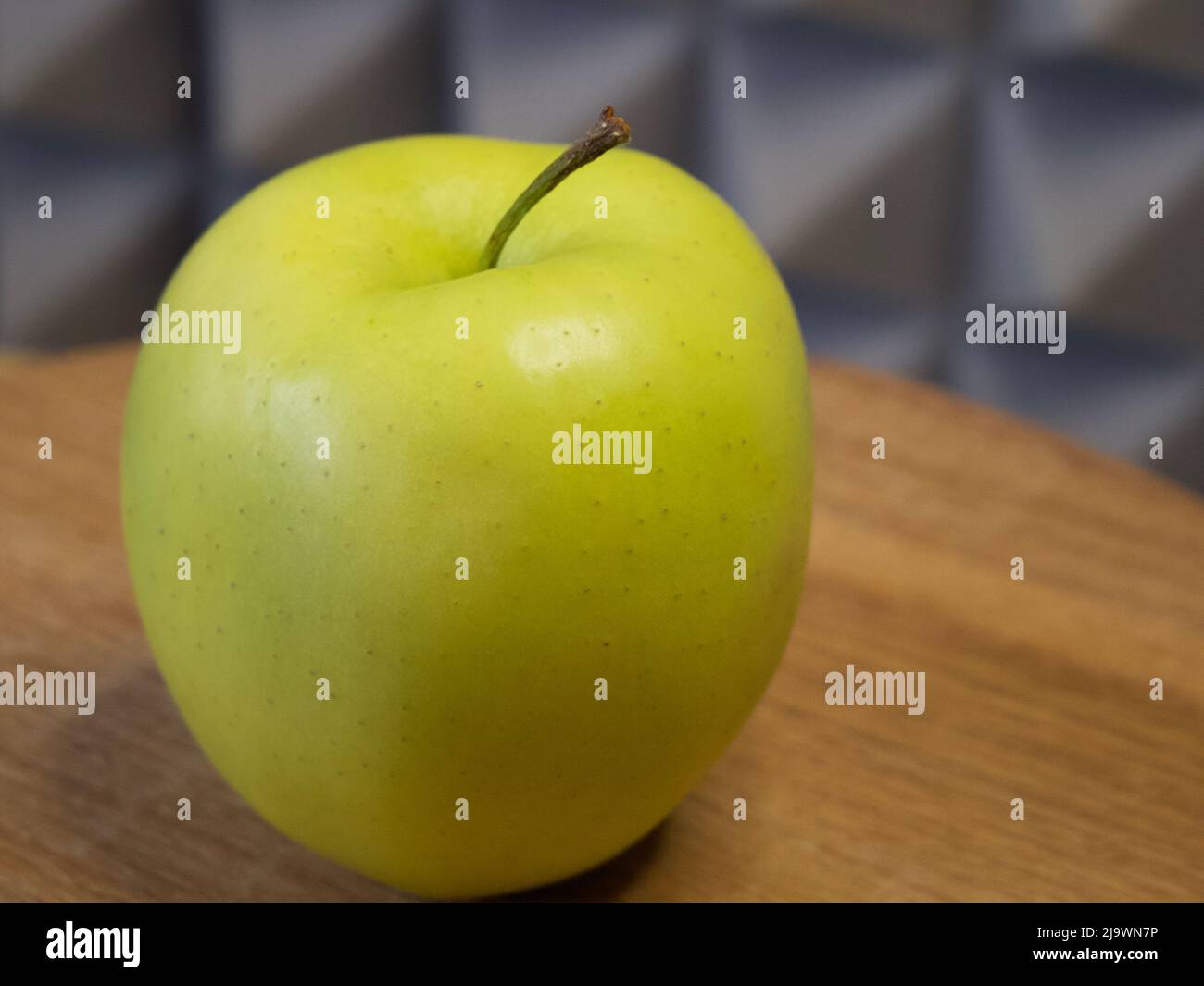 Golden Delicious è una mela gialla, una delle 15 cultivar più popolari negli Stati Uniti. Una mela singola su una superficie di legno, primo piano. Foto Stock