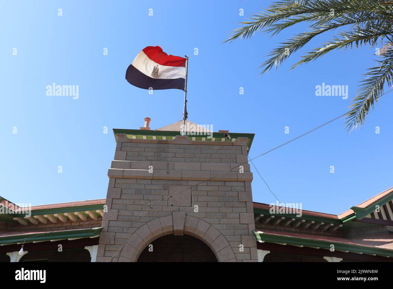 la bandiera egiziana batte sopra l'antico edificio di assuan Foto Stock