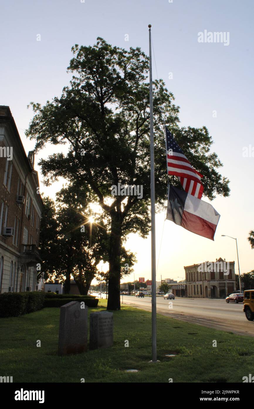 Uvalde, Stati Uniti. 25th maggio 2022. Le bandiere volano a metà del personale al tribunale della contea di Uvalde mentre il sole sorge, a Uvalde, Texas, USA, il 25 maggio, 2022. Alla scuola elementare di Robb, a Uvalde, il 24 maggio 2022, si è fatto un tiro di massa che ha causato la morte di 19 bambini e 2 adulti. (Foto di Carlos Kosienski/Sipa USA) Credit: Sipa USA/Alamy Live News Foto Stock