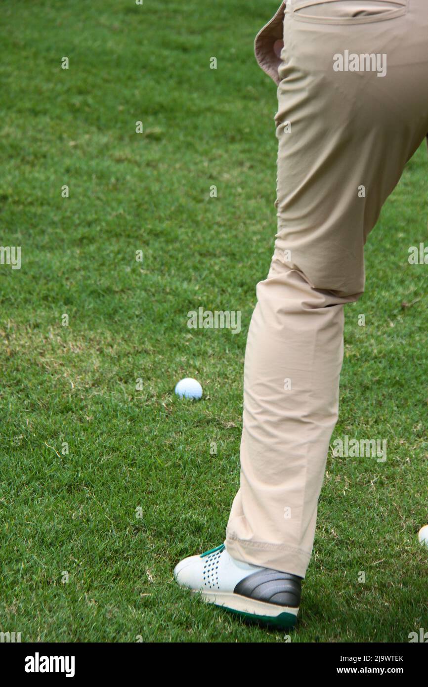Ritaglia la foto di un golfista maschile che si prepara a colpire la palla da golf sul campo da golf. Foto Stock