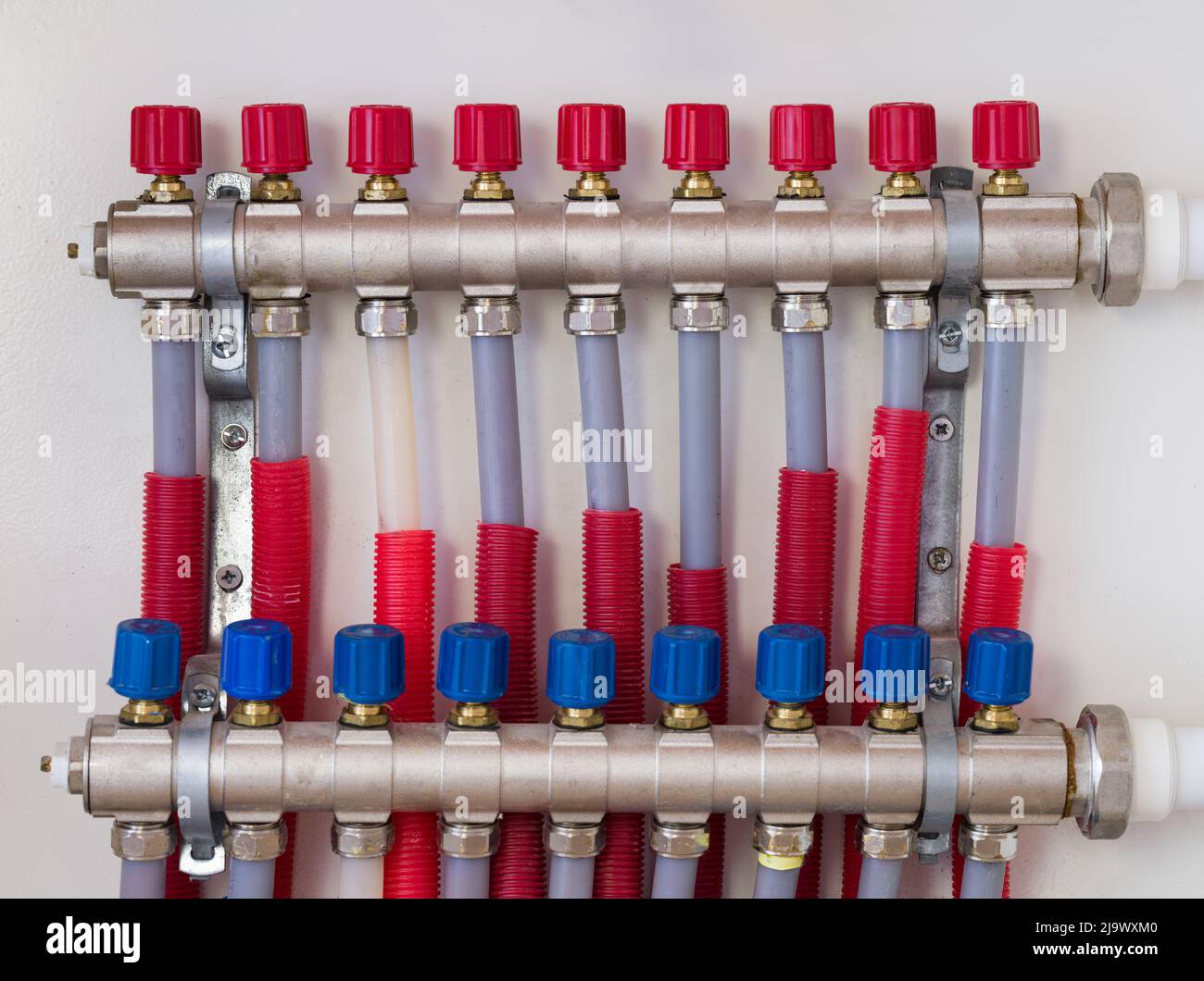Pannello pompa per riscaldamento a pavimento a casa. Valvole per il controllo della temperatura. Installazione di impianti di riscaldamento, alimentazione idrica per il riscaldamento a pavimento. Foto Stock