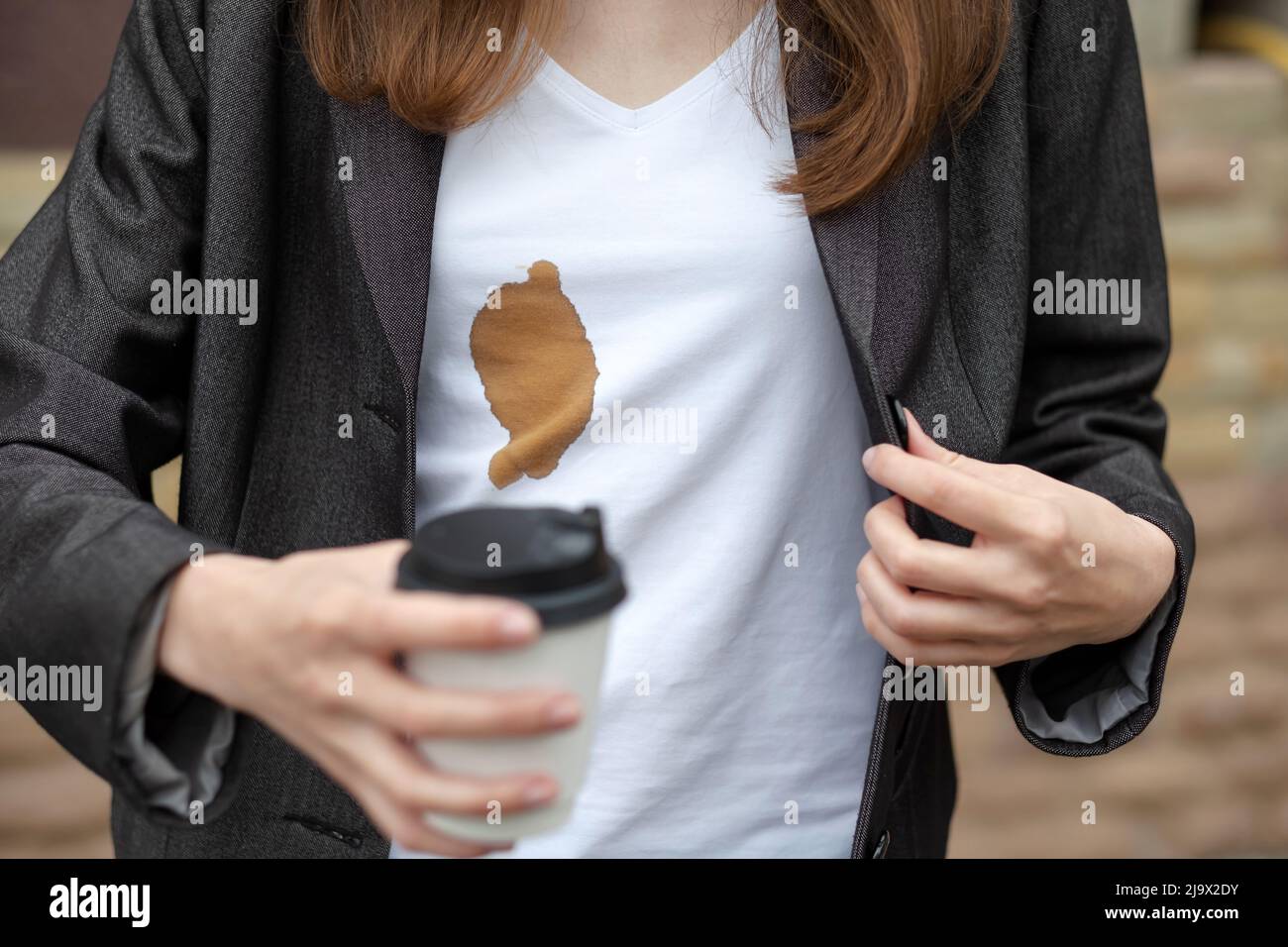 Macchie sporche di caffè versato mentre si cammina per lavorare sulla camicia bianca da donna. Il concetto di pulizia delle macchie sui vestiti Foto Stock