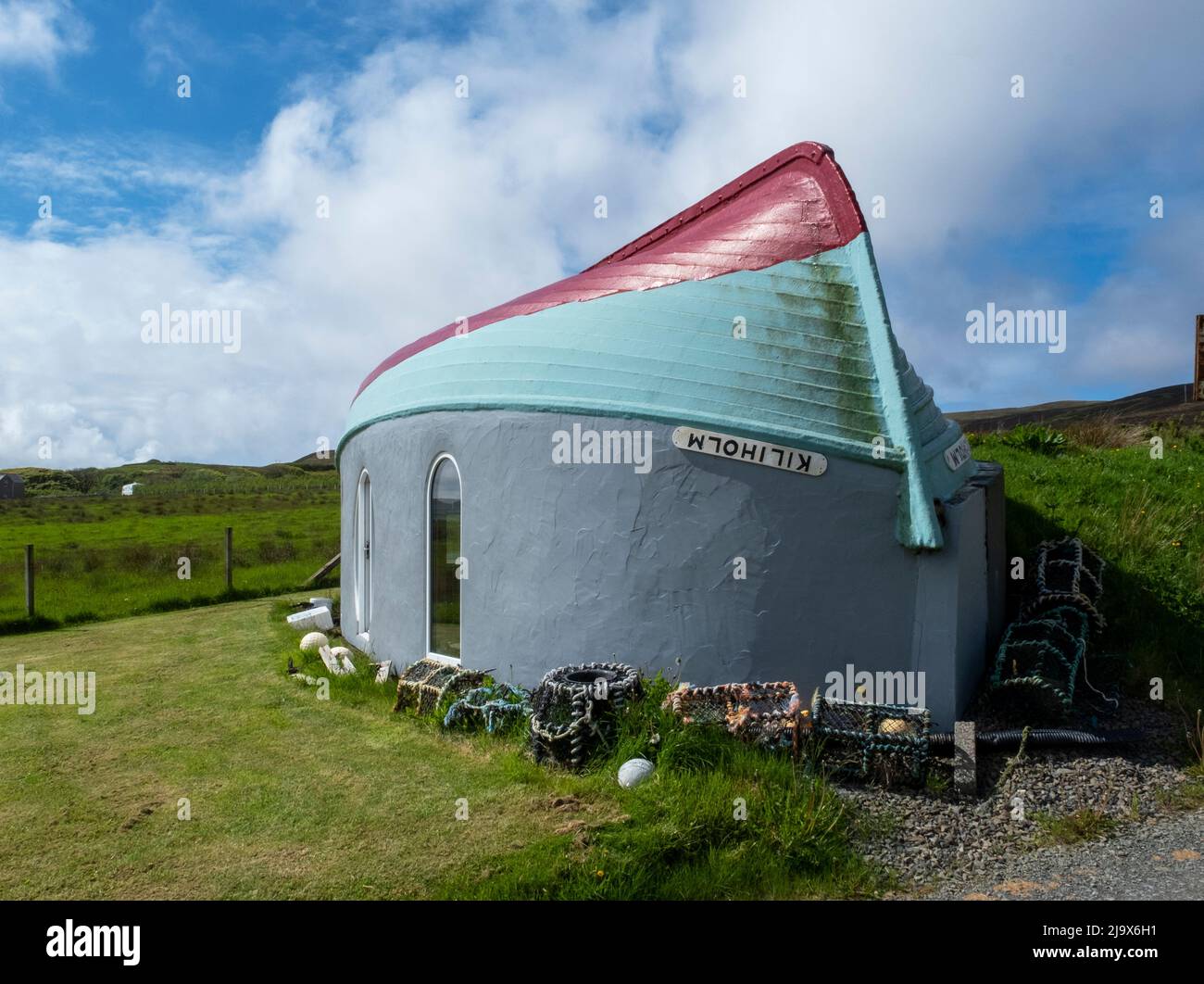Stravagante costruzione di boathouse, Isola di Rousay usando una barca da pesca capovolta come tetto per un edificio con vista su Wyre Sound, Orkney, Scozia. Foto Stock