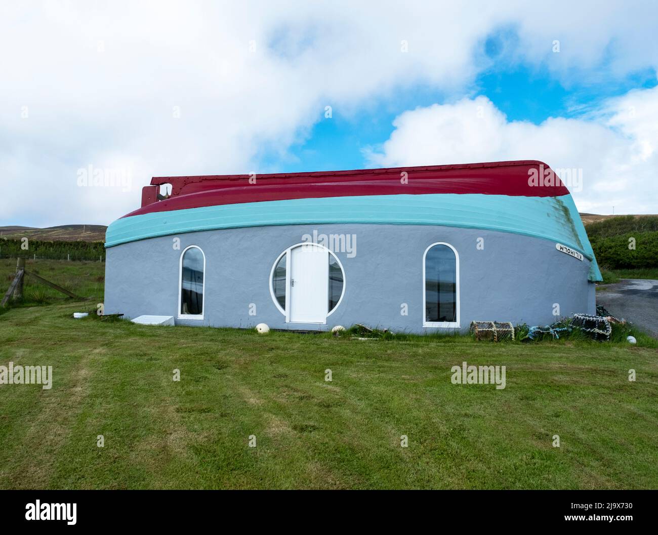 Stravagante costruzione di boathouse, Isola di Rousay usando una barca da pesca capovolta come tetto per un edificio con vista su Wyre Sound, Orkney, Scozia. Foto Stock