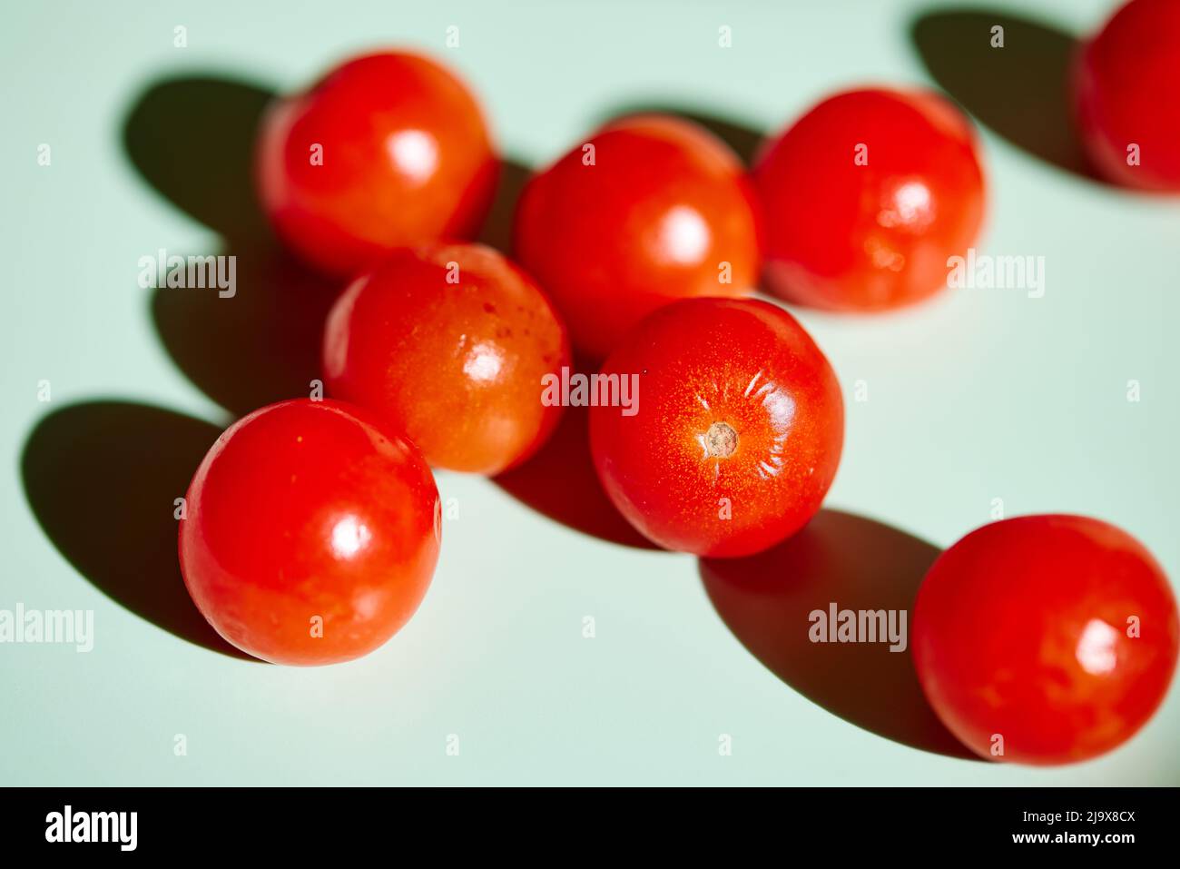 Pomodori ciliegini su sfondo verde chiaro Foto Stock