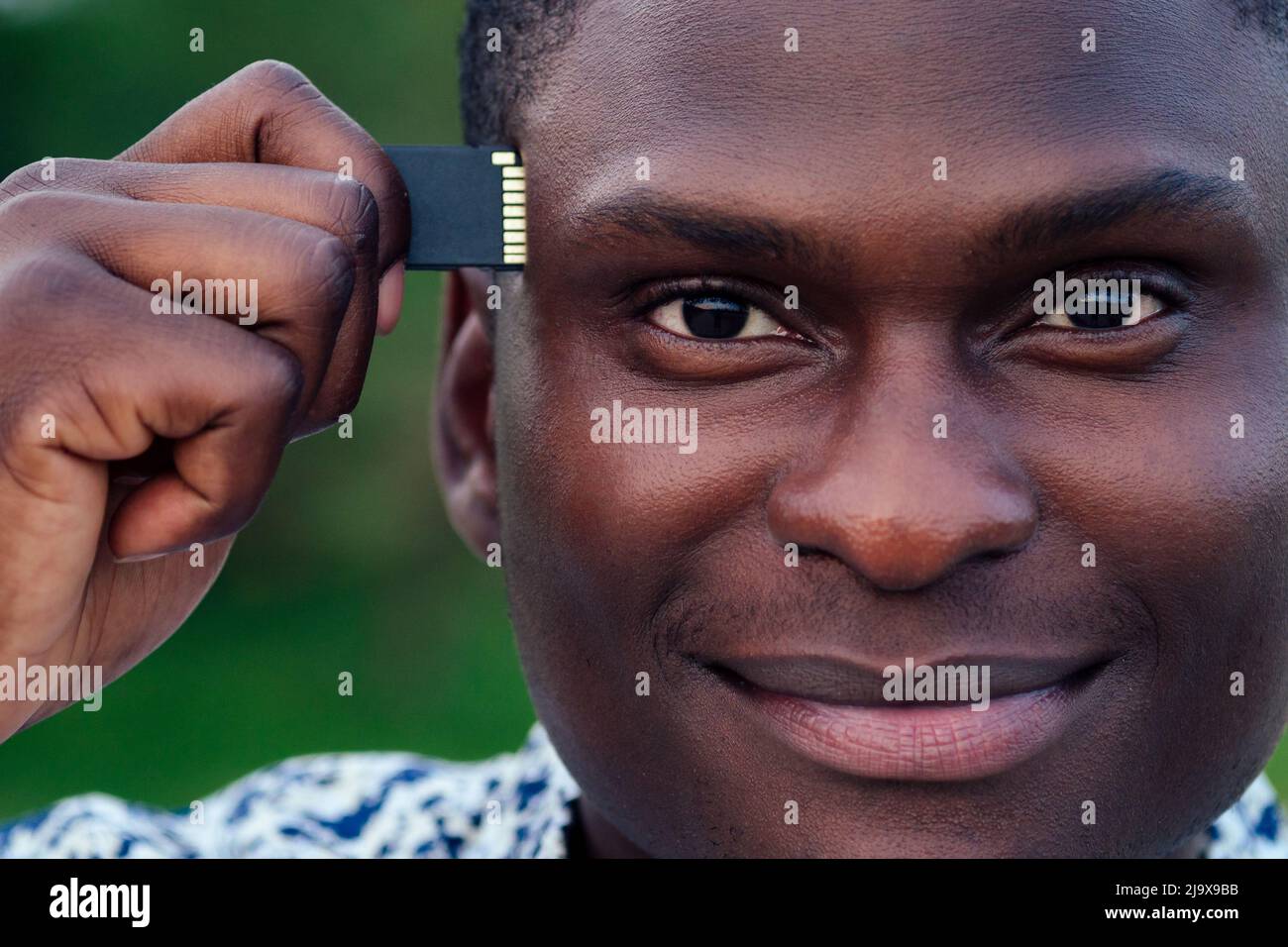 Nero afroamericani uomini ispanici businessman collegamento USB flash memory stick alla sua testa closeup ritratto. Il concetto di miglioramento e. Foto Stock