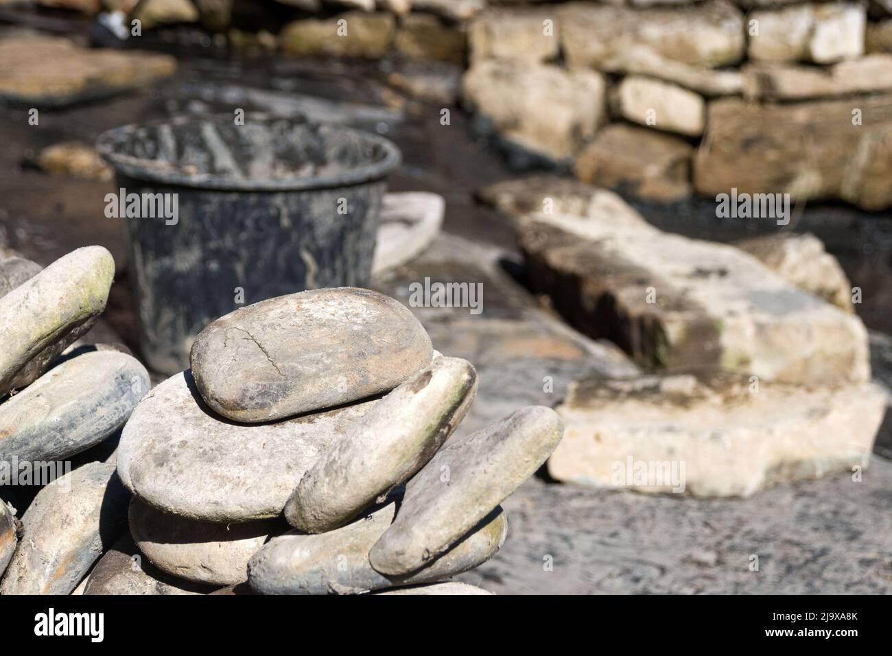 Grandi pietre sporche sullo sfondo della piscina. Costruzione e pulizia di un laghetto ornamentale nel giardino. Disegno paesaggistico. Foto Stock