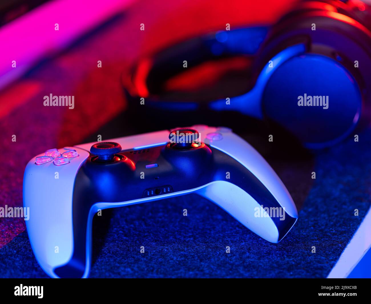 Accessori per videogiochi - gamepad e cuffie su sfondo tecnologico. Illuminazione al neon. Non ci sono persone nella foto. Videogiochi, electroni Foto Stock