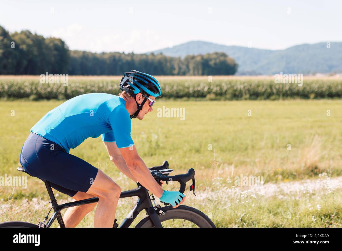 Vista laterale di un ciclista caucasico maschile, in abbigliamento sportivo  blu con casco e occhiali da sole, su una bicicletta da corsa Foto stock -  Alamy