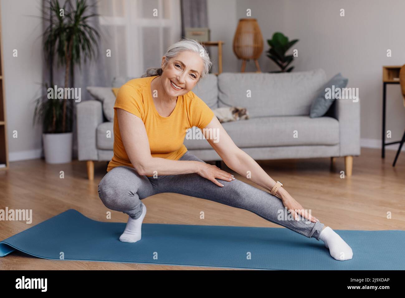 Donna anziana attiva che fa esercizi di stretching durante il suo allenamento domestico, l'allenamento, il mantenimento della forma e sano Foto Stock
