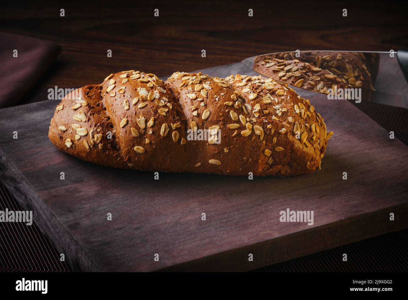 Pane rustico all'avena, fatto in casa su un asse di legno, pane multigrain Foto Stock