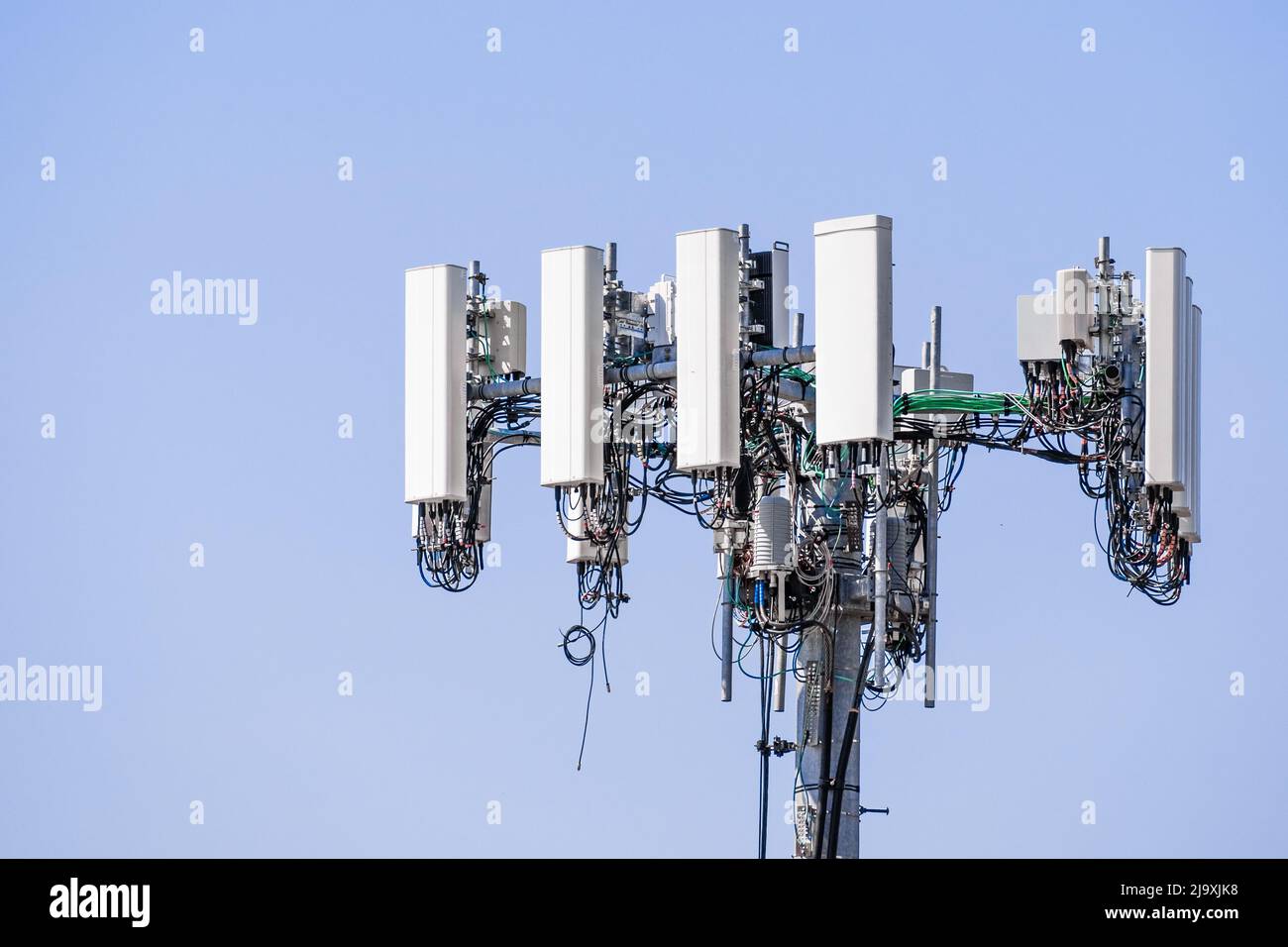 Primo piano della torre del telefono cellulare per telecomunicazioni con antenne di comunicazione wireless; sfondo blu e spazio di copia sulla destra Foto Stock