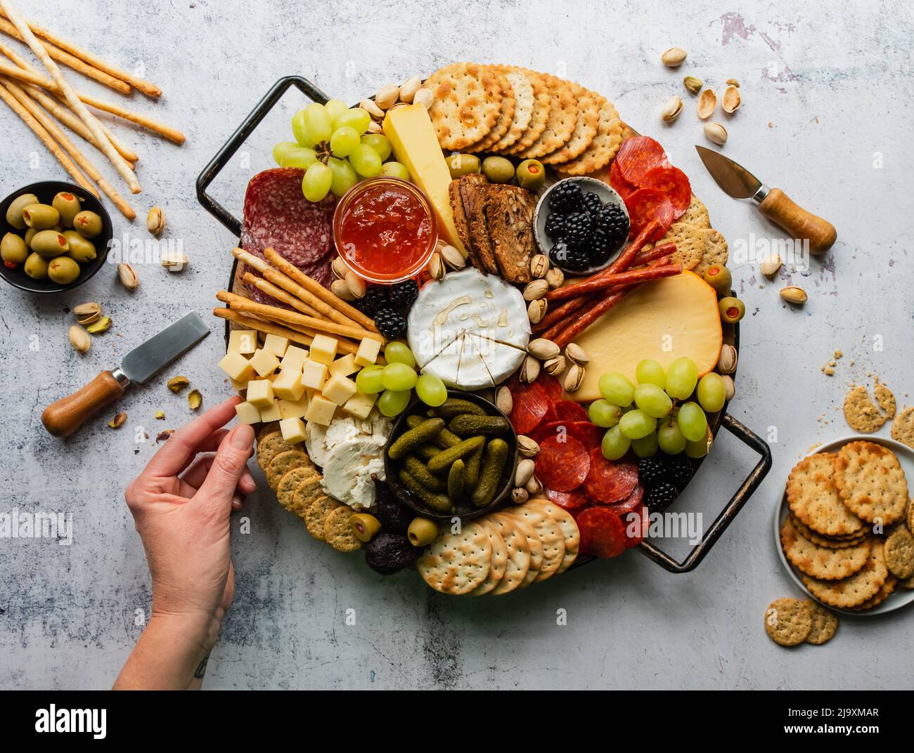 Assaggi a mano di salumi di carne, formaggio, frutta, cracker. Foto Stock