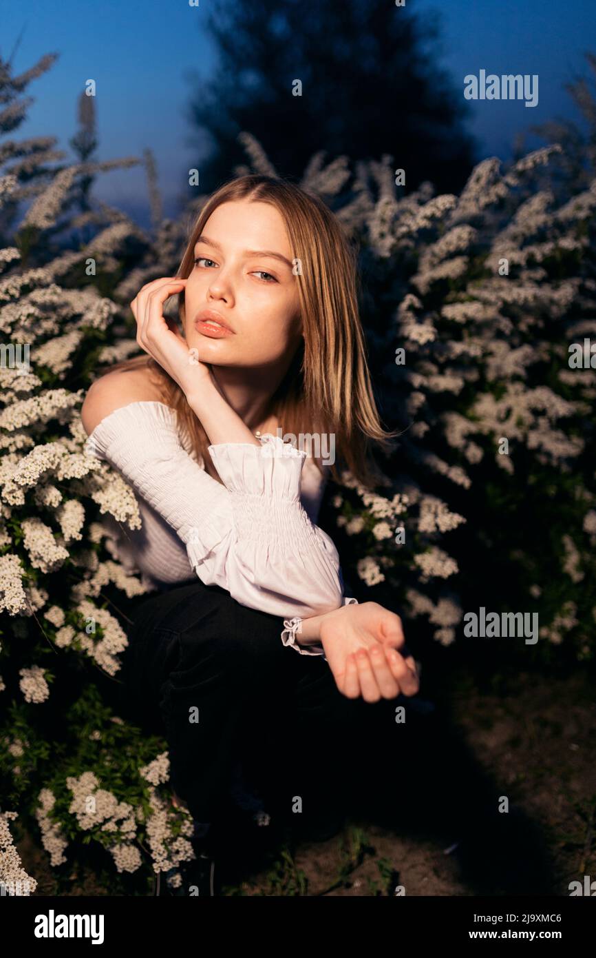 ritratto serale di una donna seduta in fiori Foto Stock