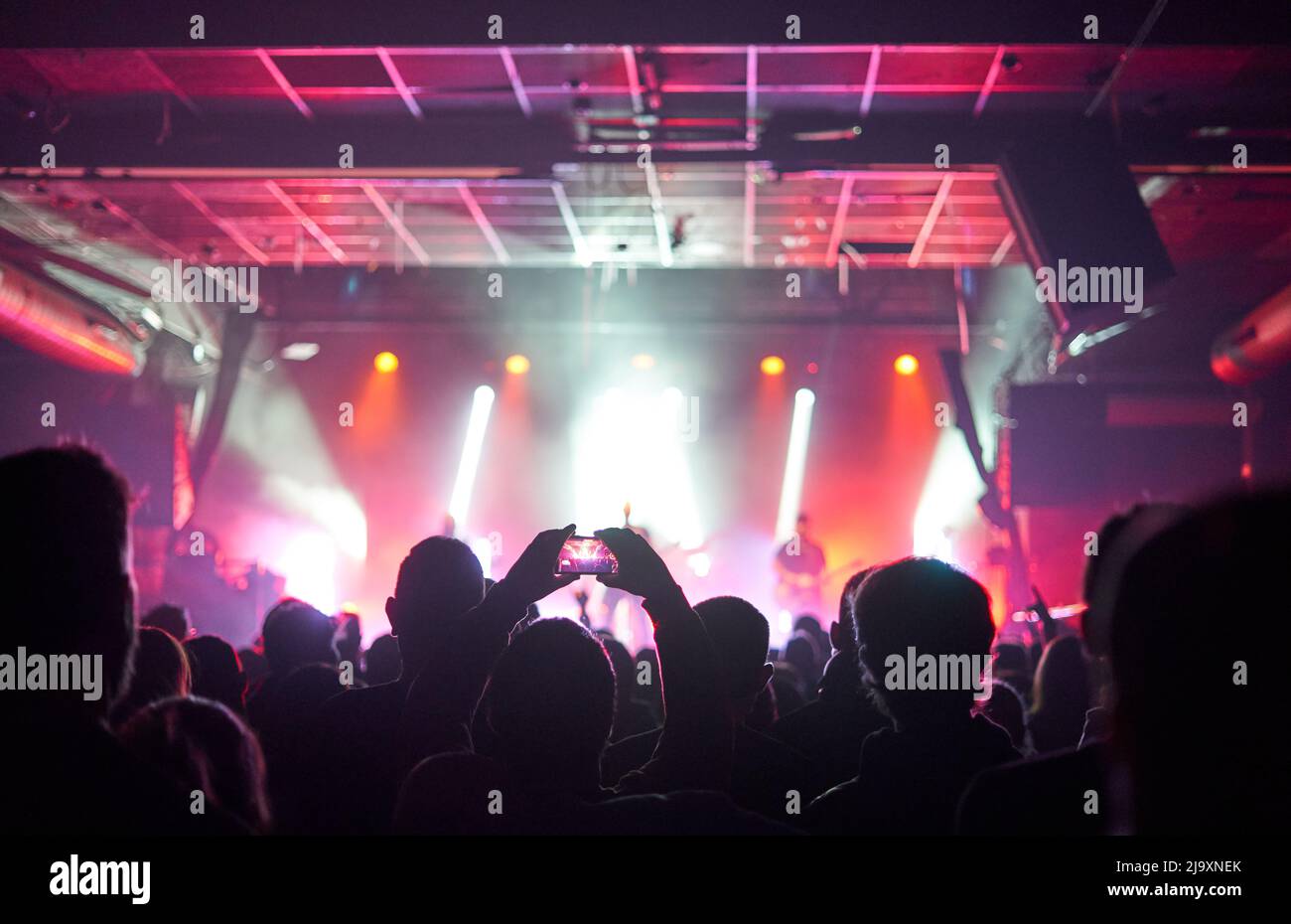 Sillhouettes di folla di concerto di fronte a luci palcoscenico luminoso Foto Stock