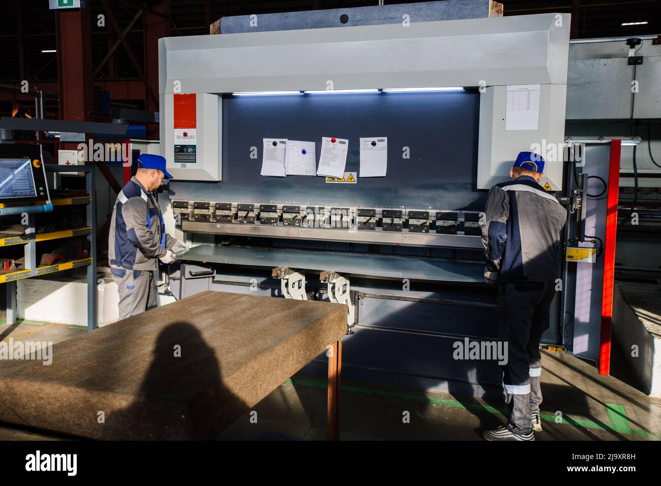 Operatori tecnici che lavorano con lamiera su pressa idraulica CNC. Foto Stock