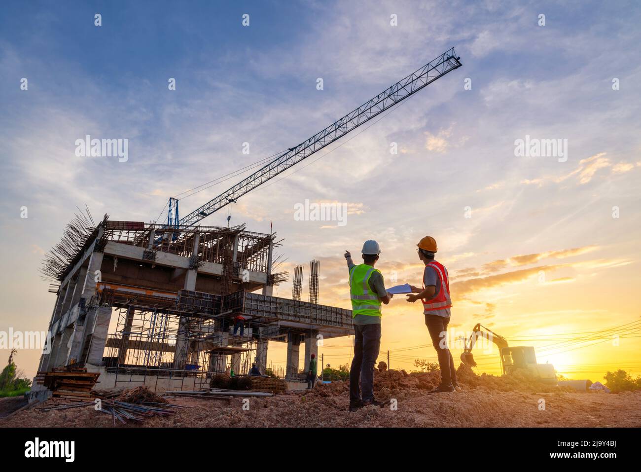 Architetto civile ingegnere e lavoratore di controllo del progetto in cantiere background, cantiere al tramonto in serata. Silhouette del costrutto Foto Stock