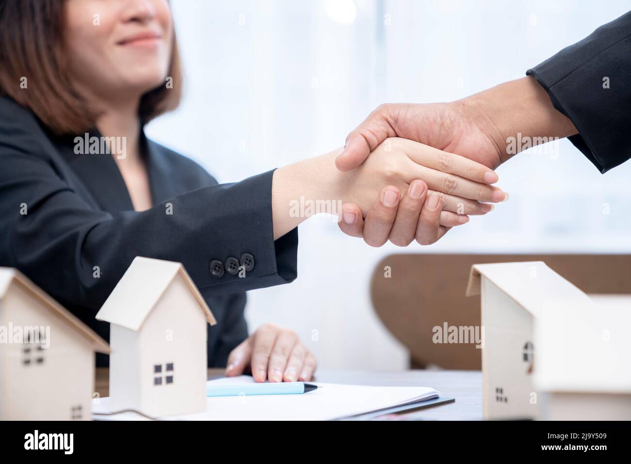Suggellando un concetto di trattativa, l'agente immobiliare agita le mani con il cliente dopo la firma del contratto. Foto Stock