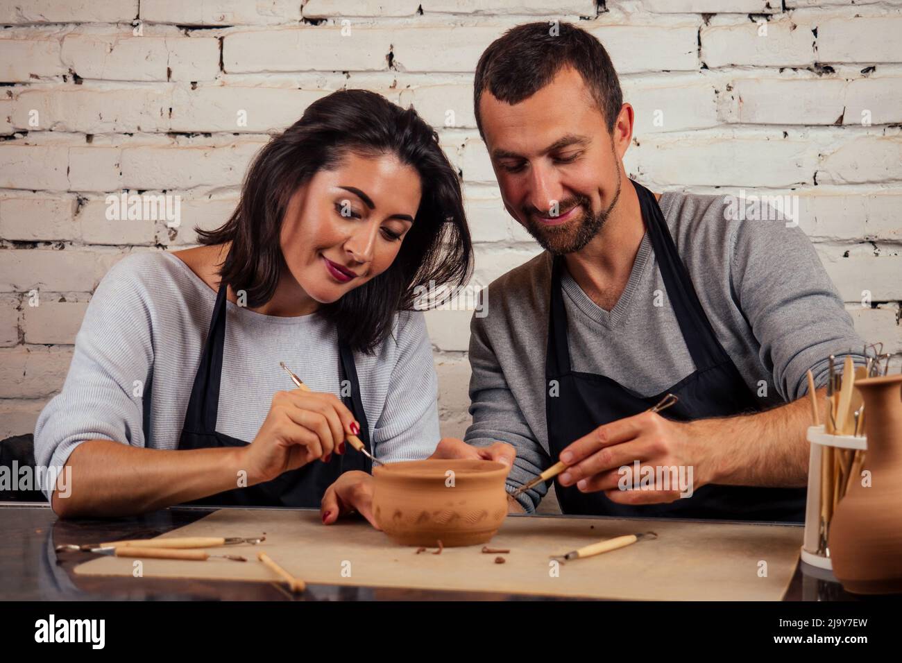 famiglia felice in una vacanza congiunta creativa. coppia romantica in amore lavorando insieme su ruota del vasaio e scolpendo vaso di argilla, un uomo bearded e un giovane Foto Stock