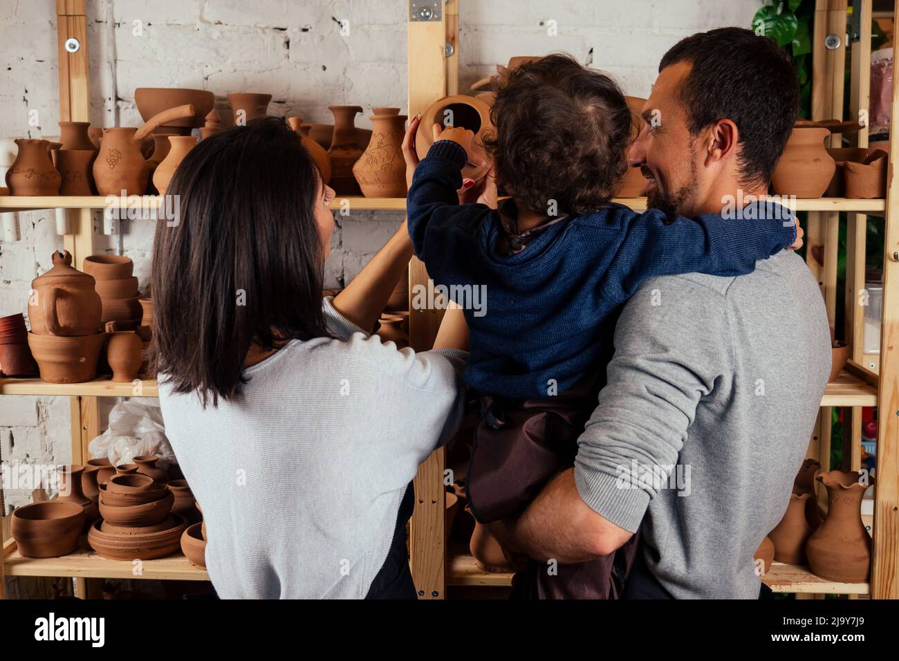 Giovane famiglia caucasica felice con figlio che lavora su ceramica shop.bella madre con papà e ragazzino che fa vaso di ceramica nella classe di arte della ceramica Foto Stock