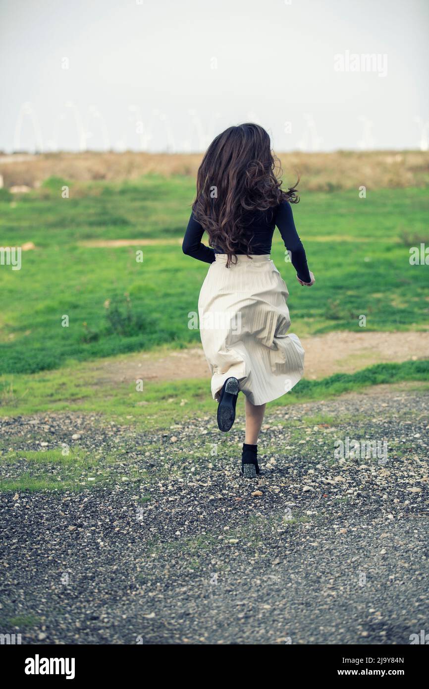 Giovane donna che corre via sul campo Foto Stock