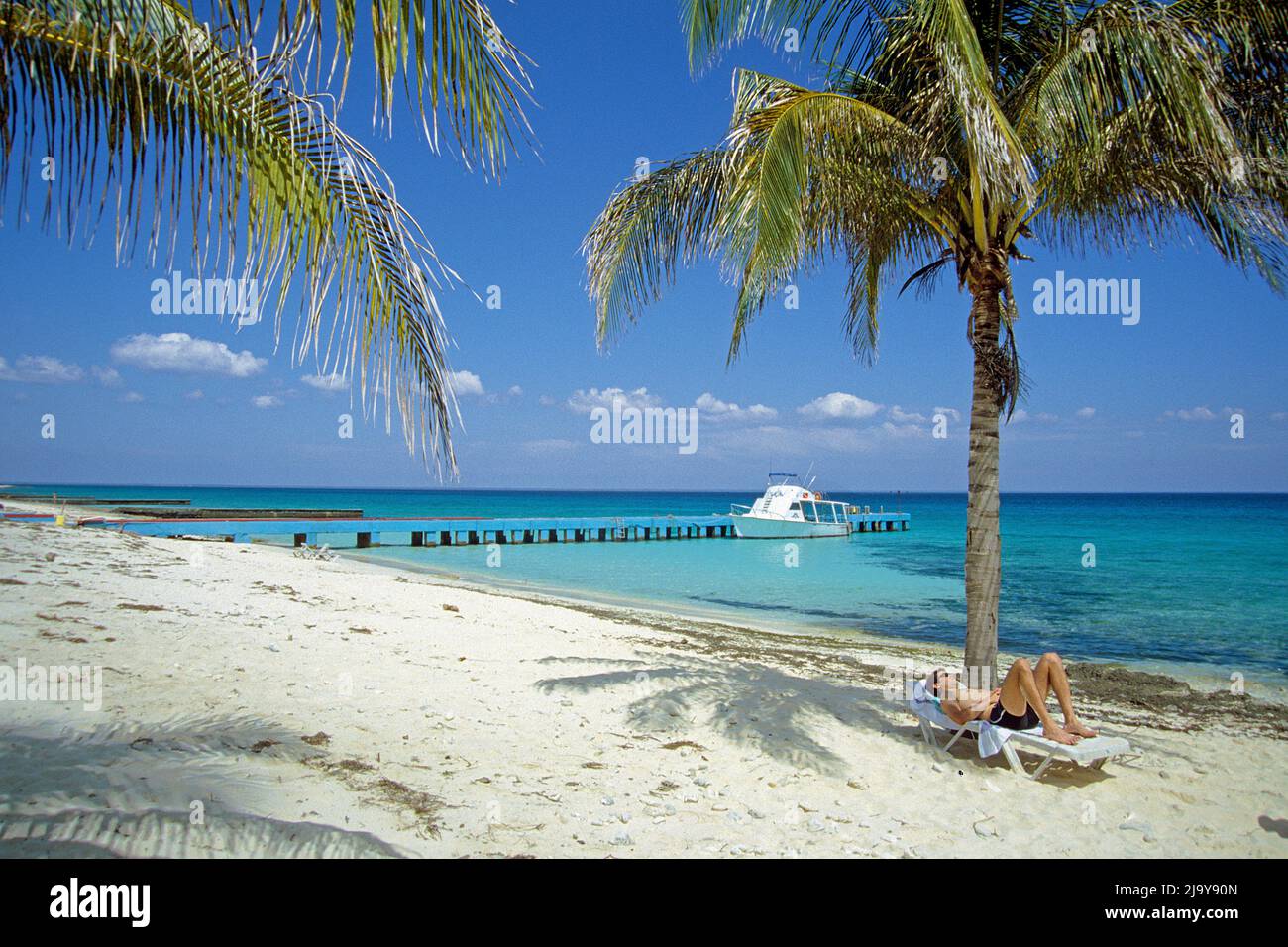 Tourist auf einer Sonnenliege unter einer Palme am Strand von Maria la Gorda, Pinar del Rio, Kuba, Karibik | Tourist sul lettino solare sotto una palma alla Th Foto Stock