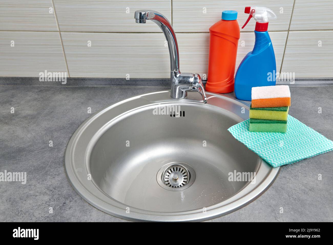 Lavello in metallo rotondo, detergente, tovaglioli e spugne in schiuma. Lavori domestici Foto Stock