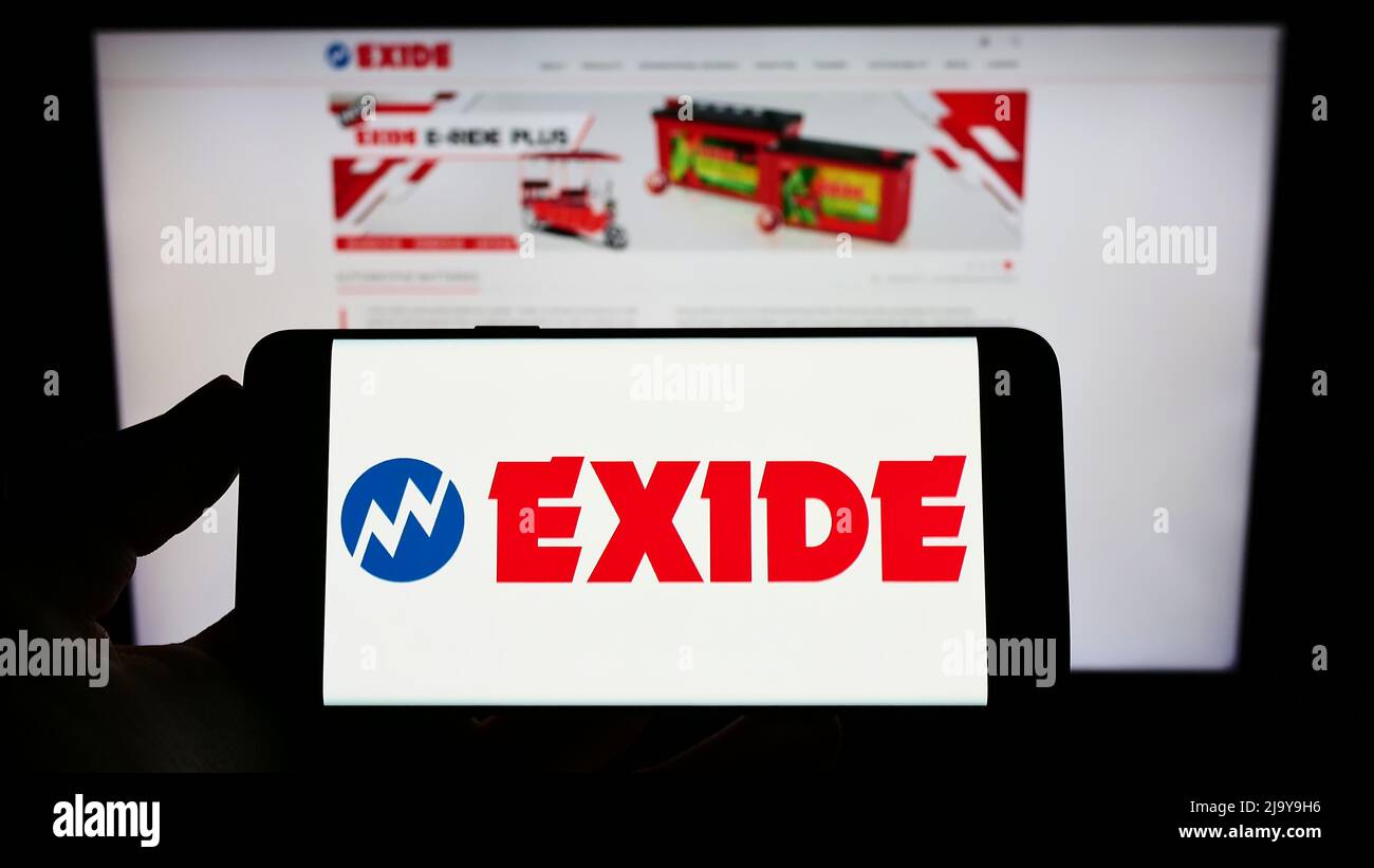 Persona che tiene il telefono cellulare con il logo della società indiana di batterie Exide Industries Ltd. Sullo schermo di fronte alla pagina web. Mettere a fuoco sul display del telefono. Foto Stock