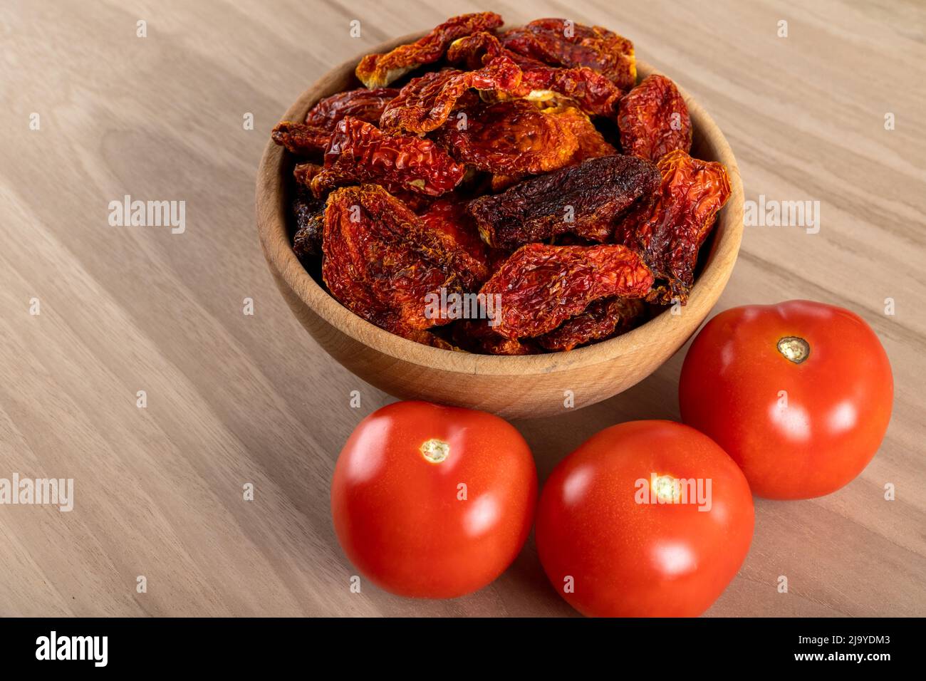 Pomodori freschi e pomodori secchi con fondo in legno Foto Stock