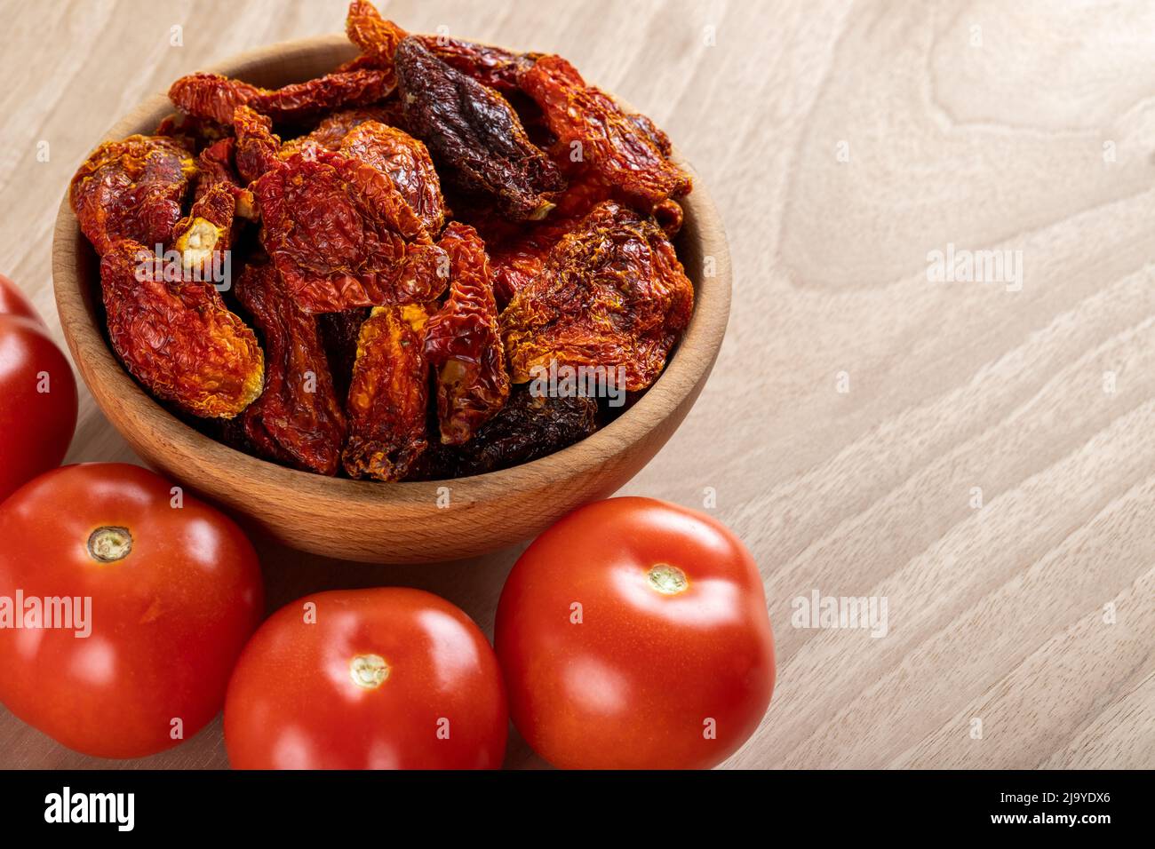 Pomodori freschi e pomodori secchi con fondo in legno Foto Stock