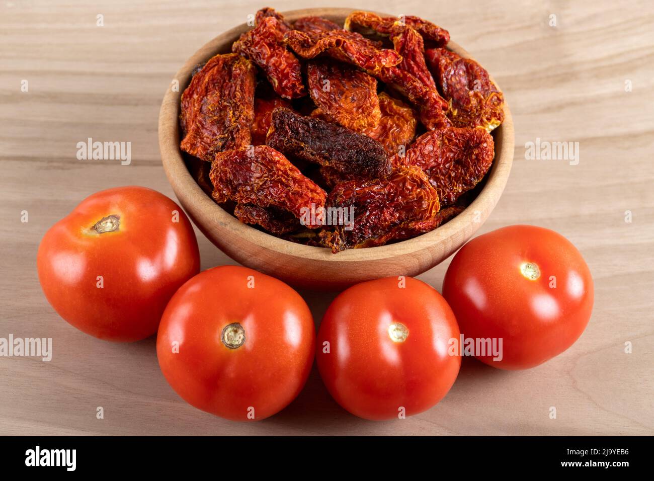 Pomodori freschi e pomodori secchi con fondo in legno Foto Stock