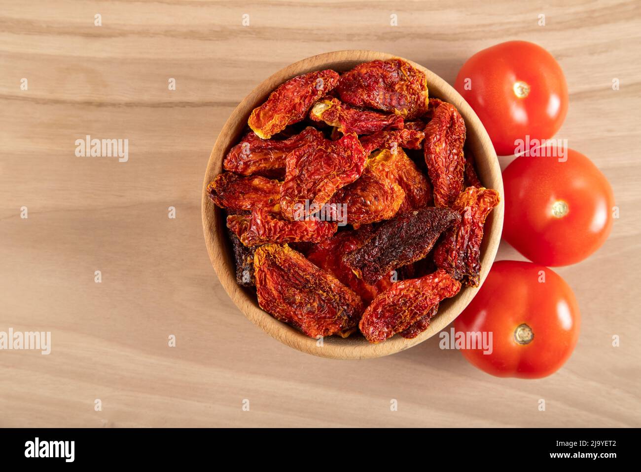 Pomodori freschi e pomodori secchi con fondo in legno Foto Stock