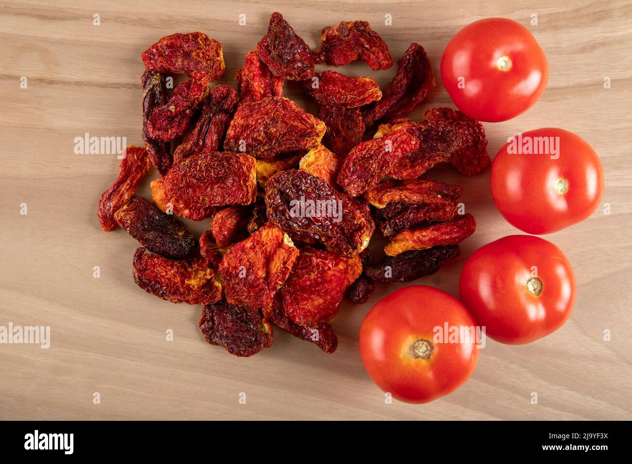 Pomodori freschi e pomodori secchi con fondo in legno Foto Stock