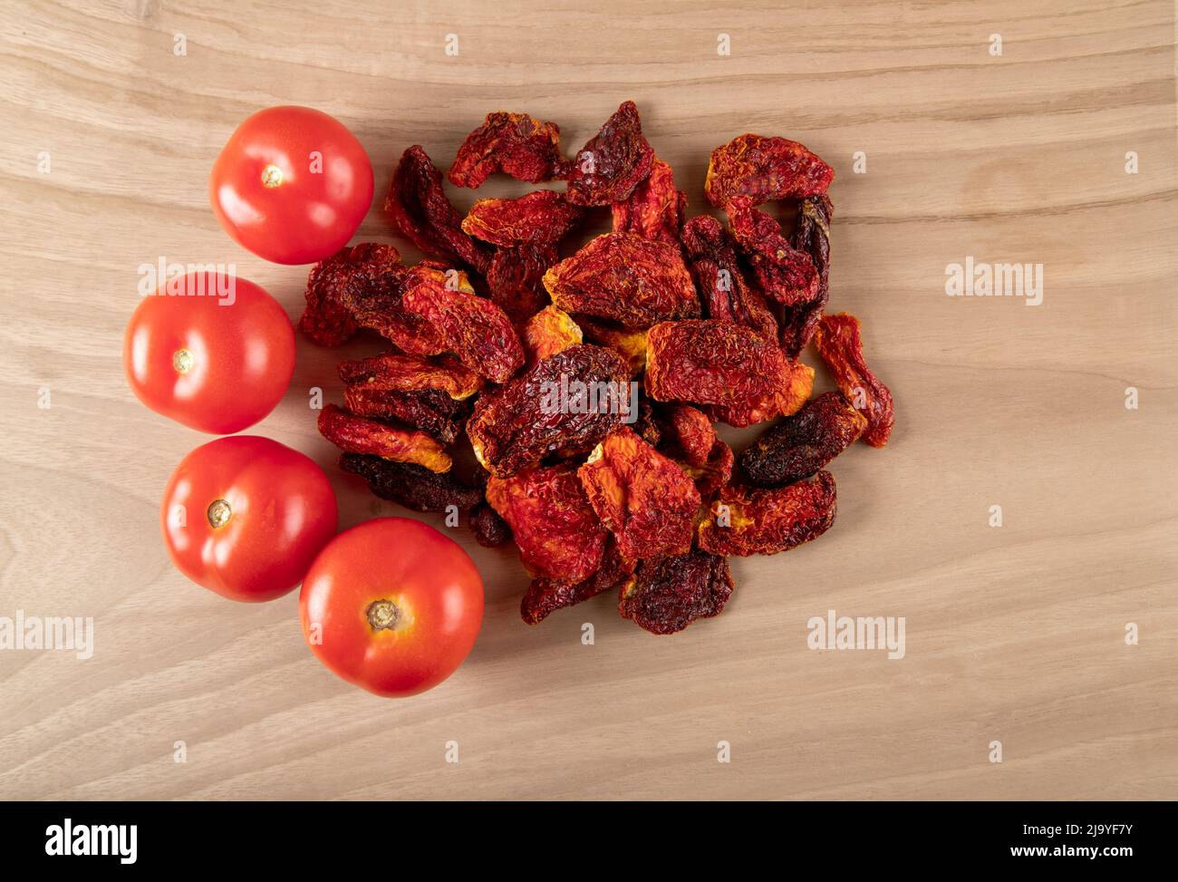 Pomodori freschi e pomodori secchi con fondo in legno Foto Stock