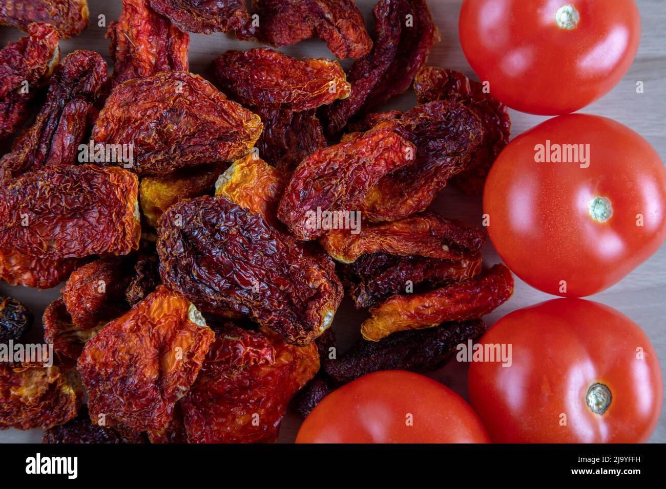 Pomodori freschi e pomodori secchi con fondo in legno Foto Stock