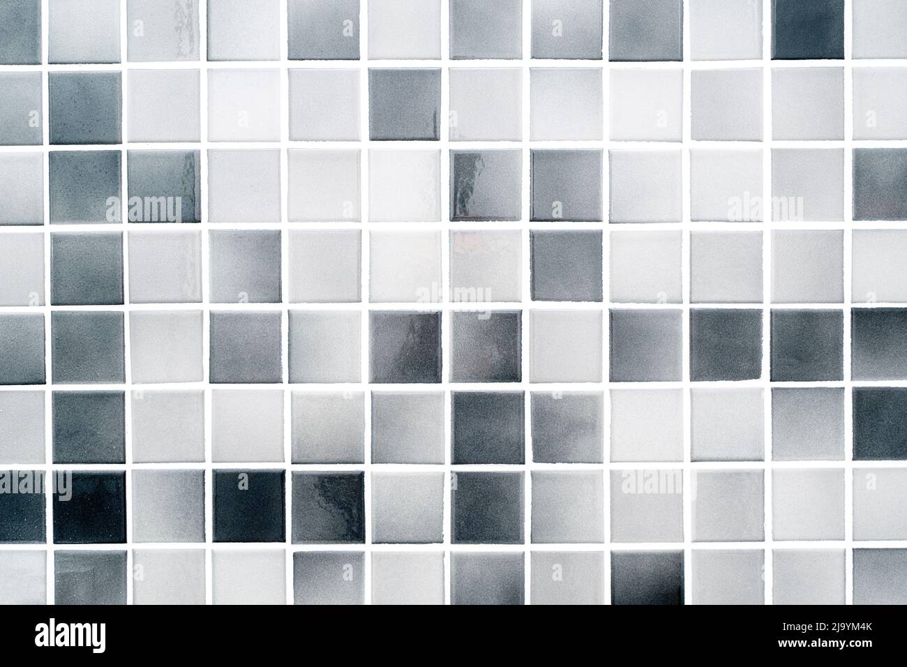 Piccole piastrelle in ceramica bianche e grigie su una parete del bagno, piastrelle moderne e pulite come texture o sfondo Foto Stock