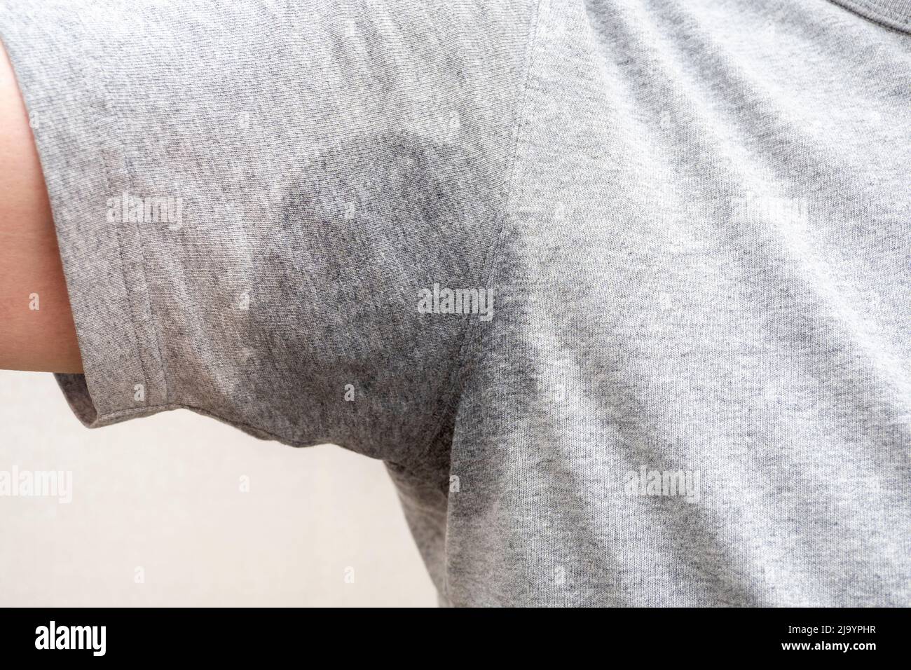 Primo piano dell'ascella sudata, macchia umida dell'ascella sulla t-shirt grigia Foto Stock