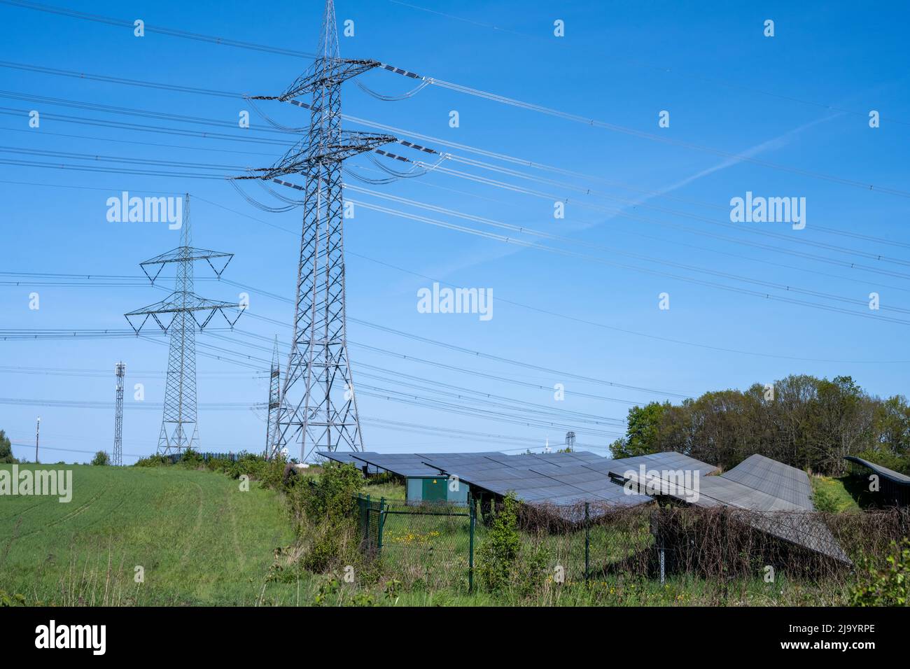 Linee elettriche con piloni e una centrale solare vista in Germania Foto Stock