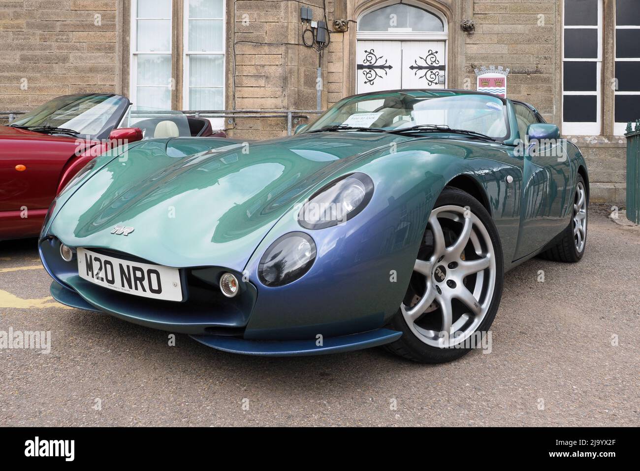 TVR Tuscan MK2 in flip Chameleon vernice blu/verde, con un motore dritto sei 3,6lt costruito nel 2005. Di fronte ad un vecchio edificio in pietra. Foto Stock