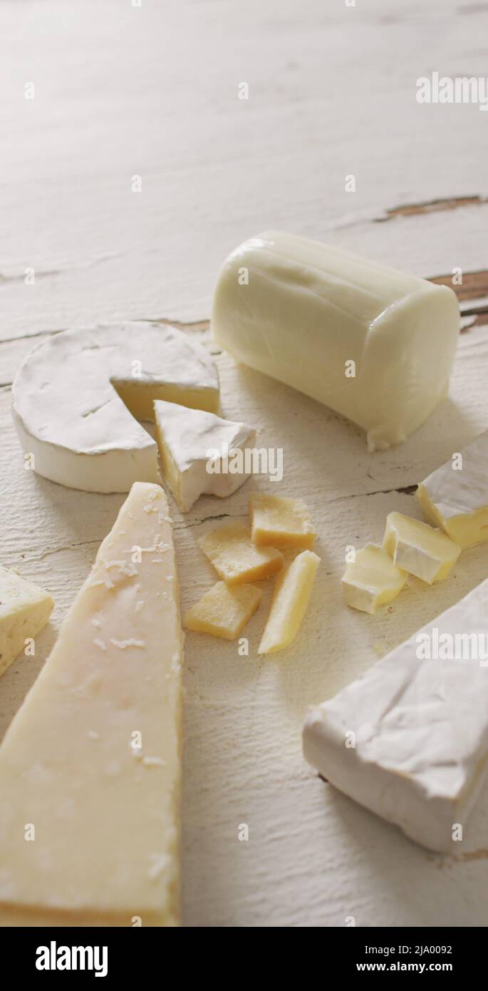 Immagine verticale di pochi tipi di formaggio su sfondo bianco rustico Foto Stock
