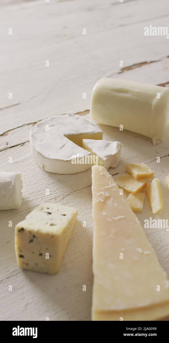 Immagine verticale di pochi tipi di formaggio su sfondo bianco rustico Foto Stock