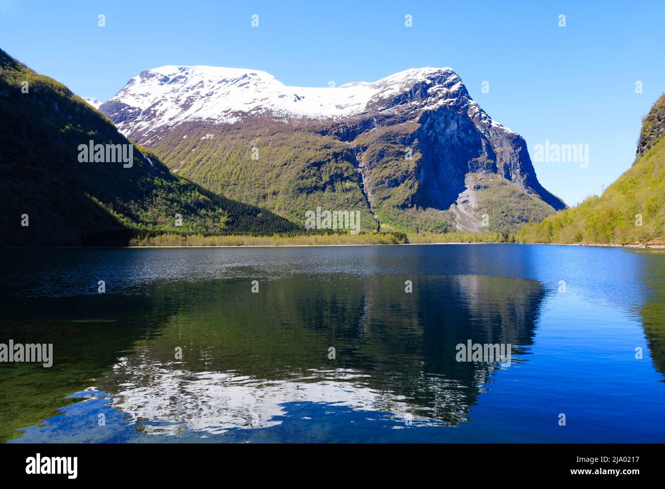 Vista sul lago Lovatnet da Kjenndalstova, Norvegia. Cime di montagna innevate e acqua blu limpida. Foto Stock