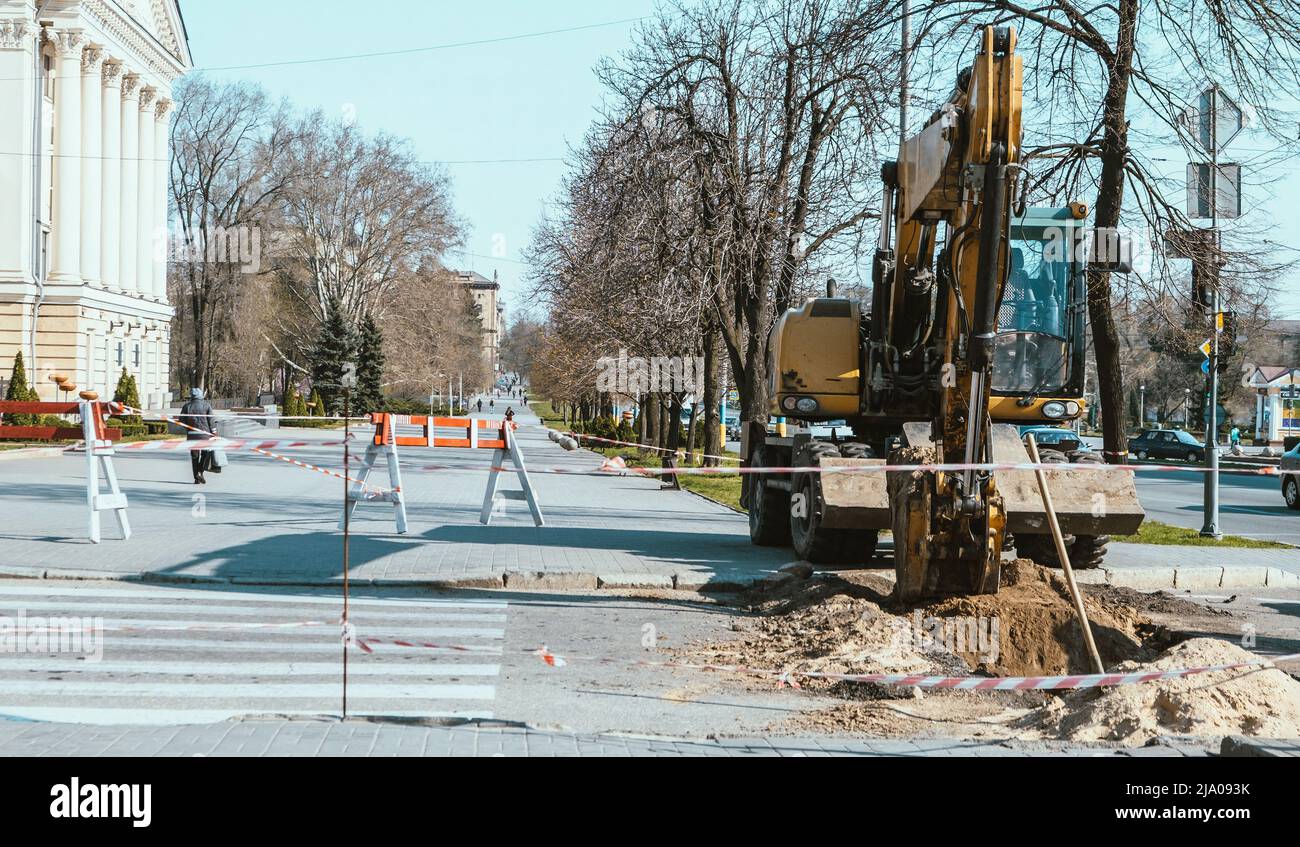 L'escavatore sta lavorando alla costruzione di strade. Escavatore in città. Trattore gommato, macchine pesanti in funzione. Foto Stock