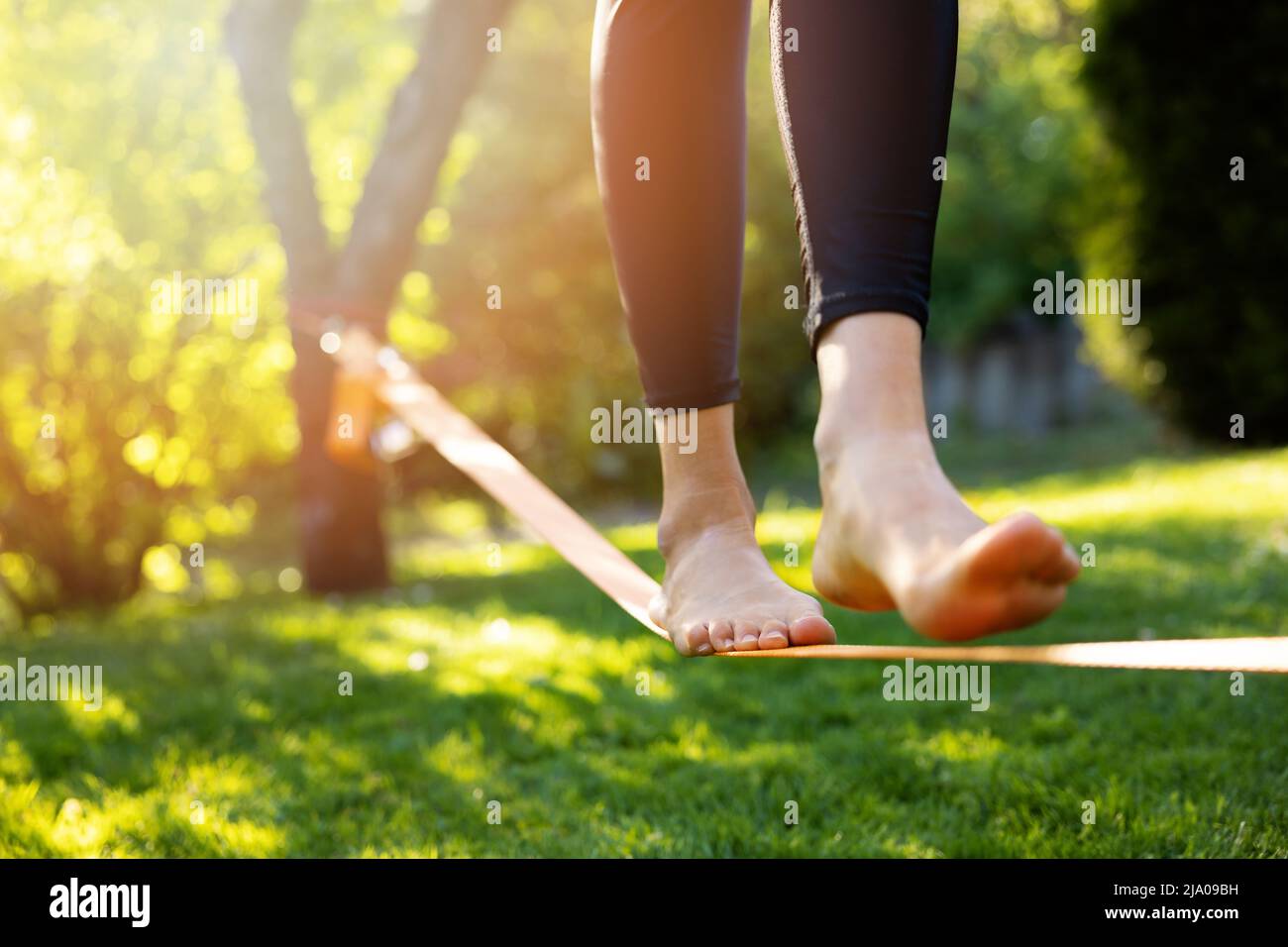 donna che cammina su una slackline in un parco al tramonto. core equilibrio allenamento Foto Stock