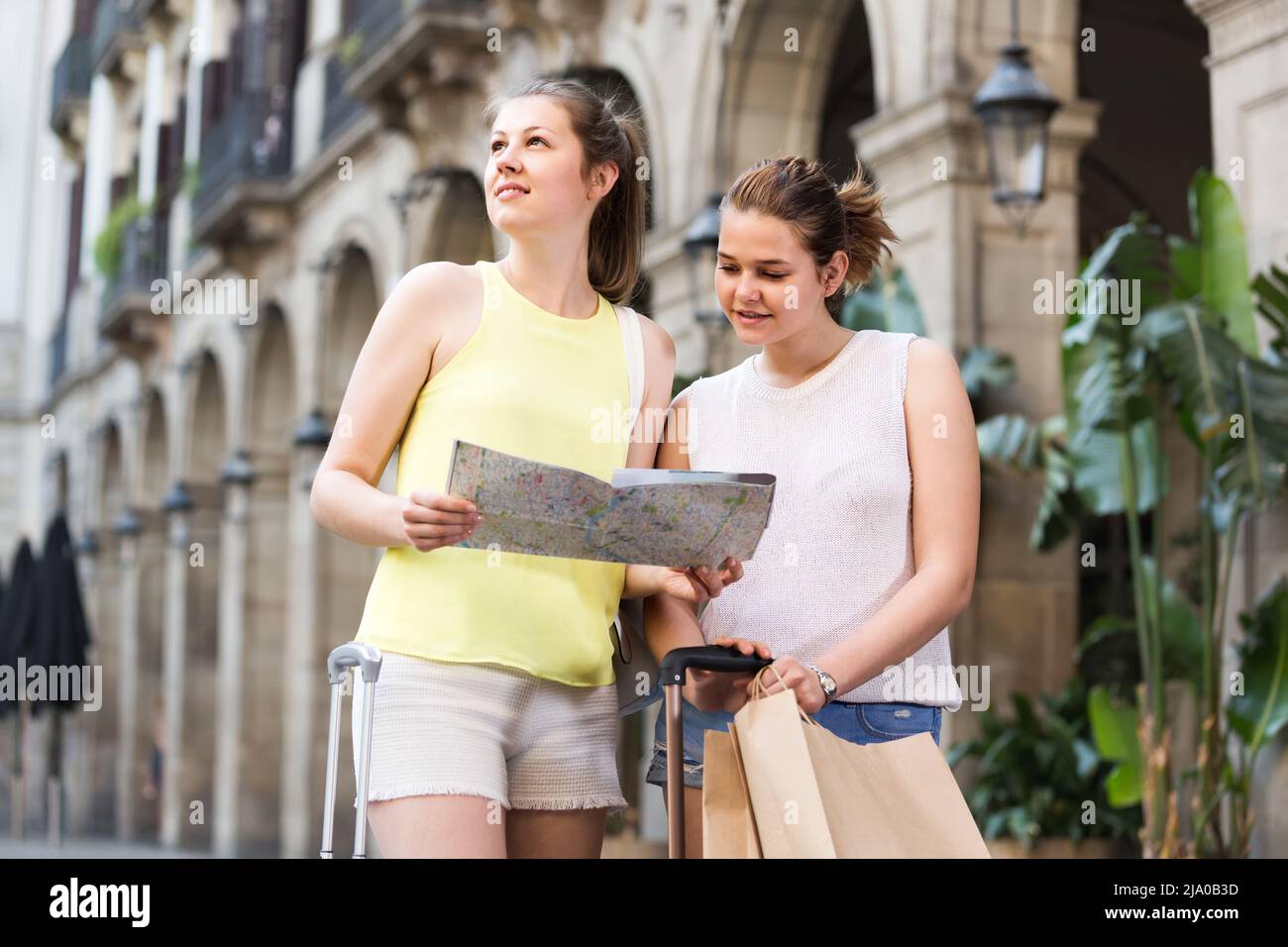 donne amici che hanno una mappa e la ricerca di itinerario turistico in città Foto Stock