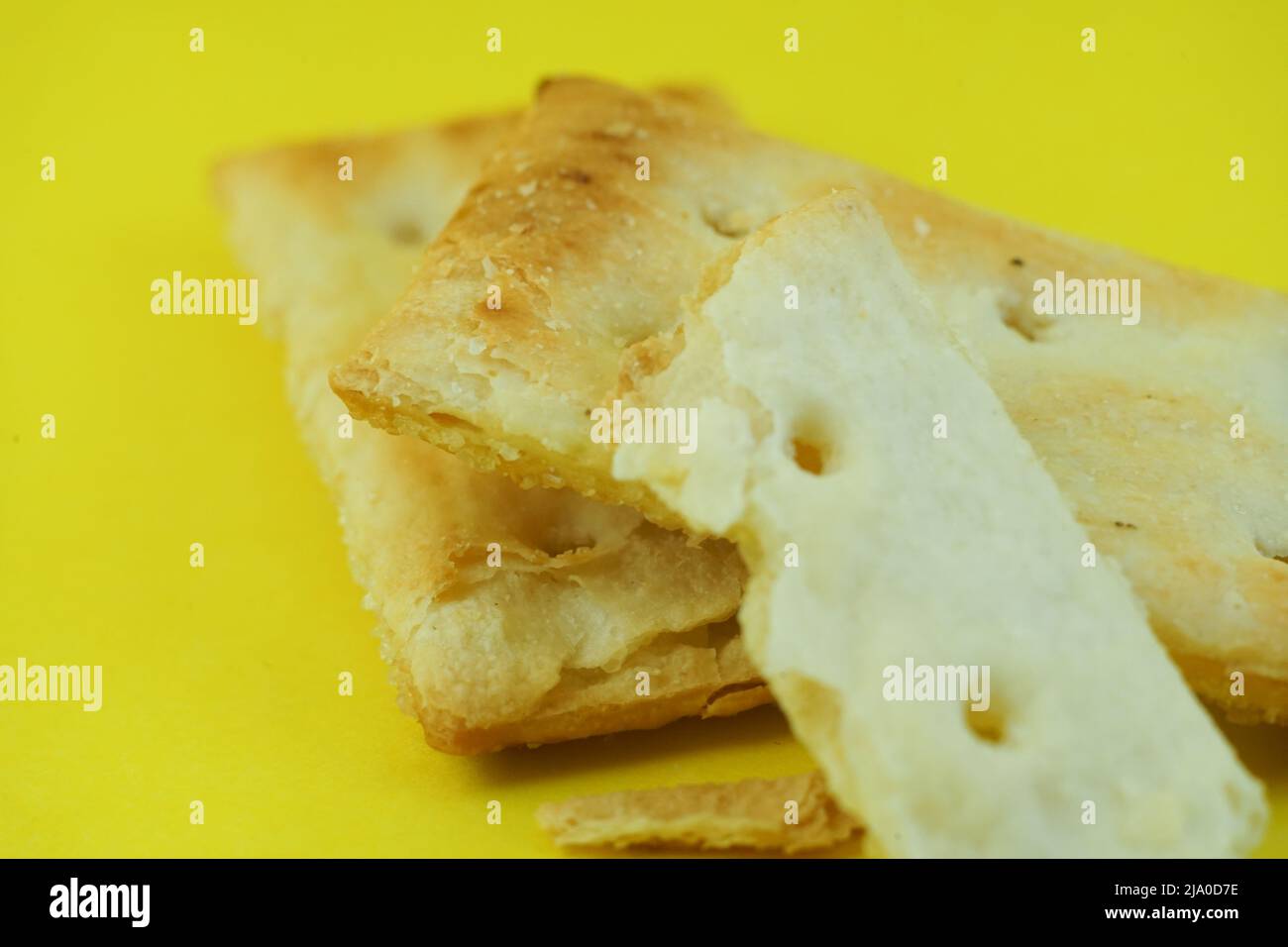 Due lati di un delizioso cracker quadrato, isolato su sfondo giallo Foto Stock