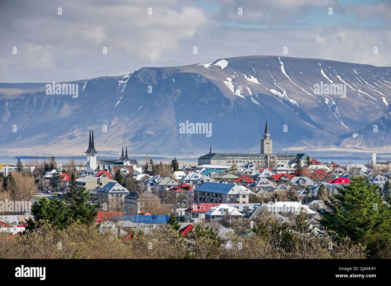 Reykjavik, Islanda, 25 aprile 2022: Vista dalla collina di Öskjuhlíð con Háteigskirkja e la scuola di Seaman che si innalzano sopra il tetto colorato, e le montagne Foto Stock