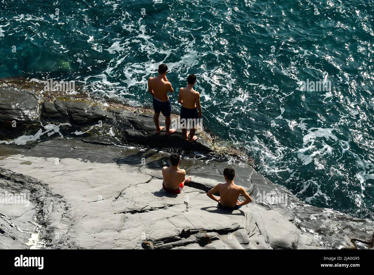 Vista su una scogliera della passeggiata di Nervi con un piccolo gruppo di adolescenti (circa 16-17 anni) che prendono il sole sulla riva, Genova, Liguria, Italia Foto Stock