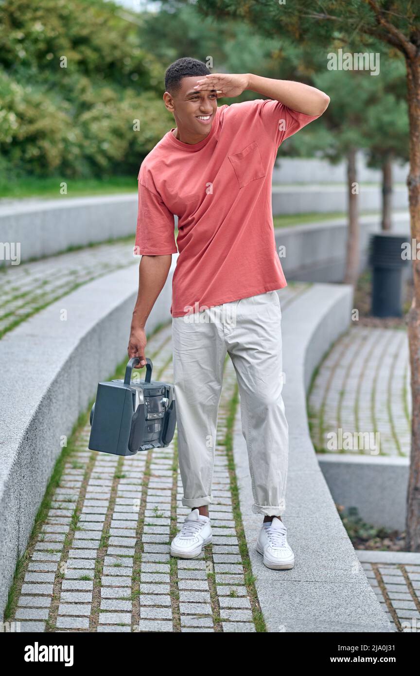 Tipo che tiene il registratore a nastro guardando lontano nel parco Foto Stock