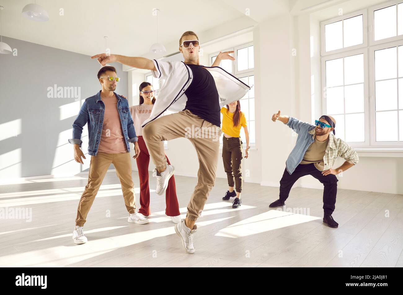 Ballerino maschile che fa balletto girare durante la pratica di danza contemporanea con gli amici in studio Foto Stock